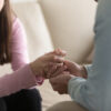 Close up view of upset couple, guy holding hands of crying woman, trying to comfort and console her, boyfriend apologizing offended lady, asking for forgiveness. Support, regret and compassion