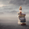 Young girl sitting on a stack of books and reading